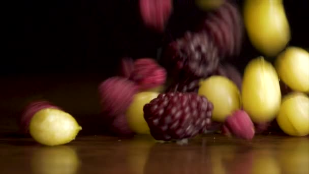 Le bacche fresche stanno cadendo sul tavolo. Mirtilli, lamponi, uva spina, mirtilli rossi cadono sul tavolo su uno sfondo nero, concetto di cibo sano — Video Stock