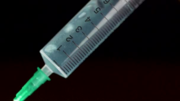 Hand holding a syringe, the syringe is filled with clear liquid is isolated on black background. Hypodermic syringe that is being filled with vaccine — Stock Video