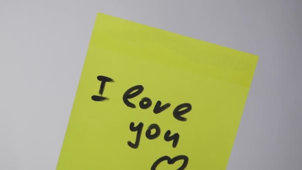 Drawing "i love you" on yellow paper. Inscription on the sticker I love you on white background — Stock Video