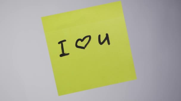 Inscription sur l'autocollant Je t'aime. Dessin "Je t'aime" et coeur sur papier jaune. Inscription Je t'aime sur l'autocollant sur le verre — Video
