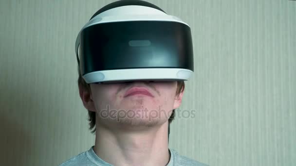 Jonge man spelen met virtual reality bril en video game controller geïsoleerd op een grijze achtergrond. Man spelen op Vr met behulp van de joystick. Virtual Reality headset op een man met video game controller — Stockvideo