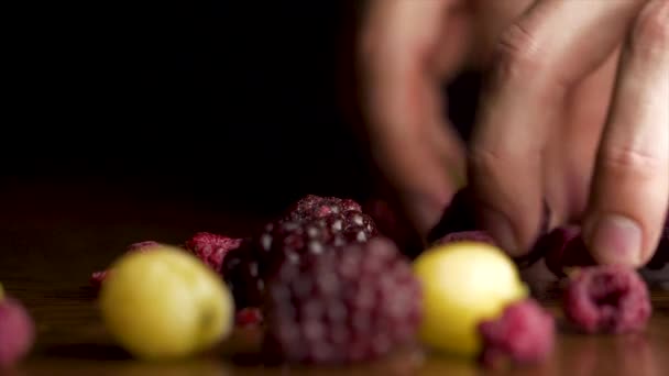 Mano masculina toma bayas y mesa de madera sobre fondo negro. Mano masculina toma BlackBerry, arándano, grosella, grosella, espino cerval de mar y otras bayas caen aislados sobre fondo negro . — Vídeo de stock