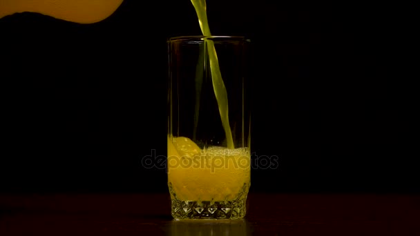 Orange Soda großes Glas, überfließendes Glas aus orangefarbenem Soda Nahaufnahme mit Blasen isoliert auf schwarzem Hintergrund. orangefarbenes Getränk. Zeitlupe. kohlensäurehaltiges Orangengetränk wird in ein Glas gegossen. — Stockvideo