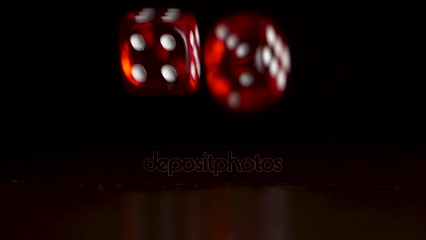 Játék kocka esik a fekete fából készült asztal, fekete háttérrel. Fekete háttér piros kocka esik. Kaszinó koncepció. Két vörös dobókocka játék fából készült asztal sötét háttér — Stock videók