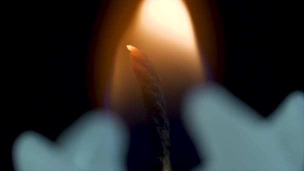 Primo piano di una fiamma di candela su uno sfondo nero. Candela bianca con sfondo scuro. Candele accese su sfondo scuro con luce calda — Video Stock