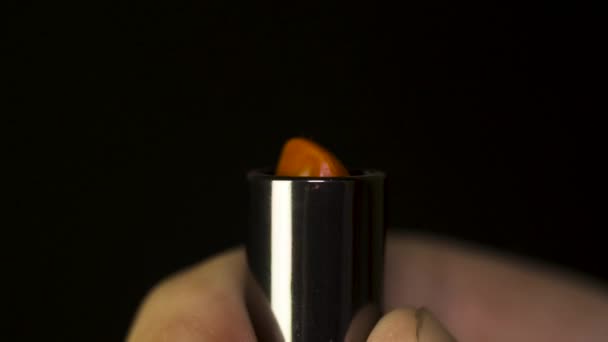 Hermoso lápiz labial rojo aislado en negro. Lápiz labial rojo macro. Descubrimiento de lápiz labial rojo en las manos de los hombres — Vídeos de Stock