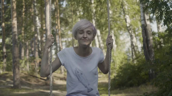 Красива дівчина на гойдалках у лісі. Молода жінка катається на гойдалках у лісі — стокове фото