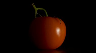Siyah bir zemin üzerine kırmızı domates. Bir taraf olanlardan. Domates tek siyah izole damla ile. siyah arka plan üzerine taze domates