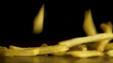 Patates kızartması siyah arka plan üzerine izole tablo üzerinde kalmaktadır. Fastfood. Patates kızartması. Siyah arka plan üzerinde uçan kızarmış patates. Siyah arka plan üzerinde kızarmış patates yığını