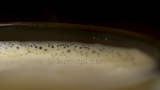 Nahaufnahme von Kaffeeschaum isoliert über schwarzem Hintergrund, von oben betrachtet. schwarzer Espressokaffee mit berauschendem Schaum in einem Glasbecher oder einer Tasse. Nahaufnahme einer Barista-Kaffeetasse — Stockvideo