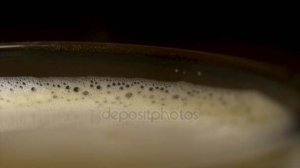 Gros plan de mousse de café isolée sur un fond noir, vue de dessus. Café expresso noir avec mousse capiteuse dans une tasse en verre ou une tasse. plan rapproché de la tasse de café barista — Video