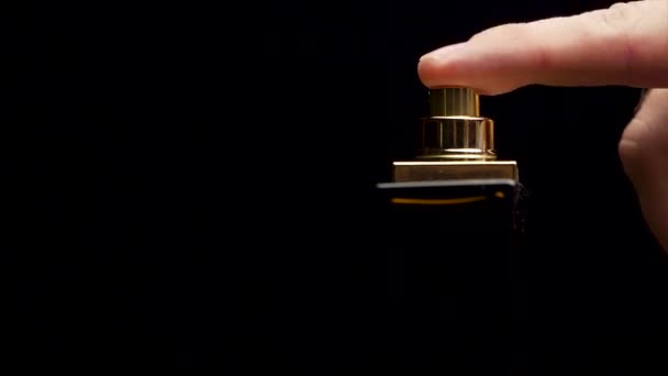 Flacon de parfum sur fond noir. gros plan d'un flacon pulvérisateur gouttes sur fond noir — Video