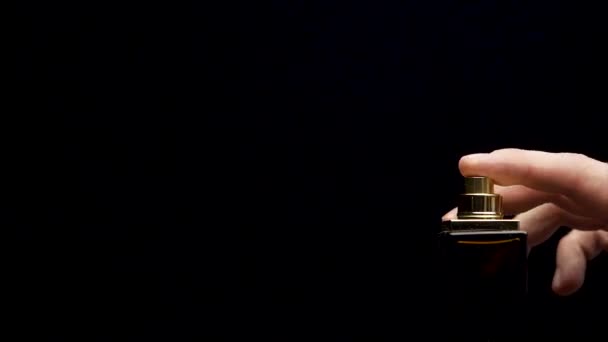 Close up of a spray bottle drops on black background. Male perfume bottle on a dark background. close up of a spray bottle drops on black background — Stock Video