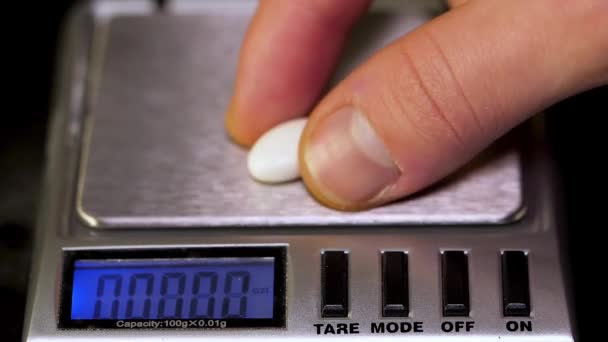 Le pharmacien met une pilule sur la balance. Pharmacien, pèse les comprimés fabriqués sur les balances de contrôle. Pilules de régime sur une échelle. Perte de poids médicament renversé 