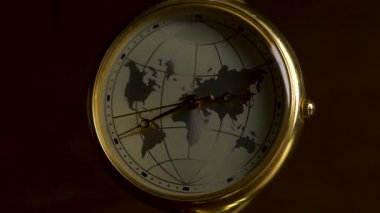 Planet Earth siyah arka plan üzerine izole ahşap bir masa üzerinde bir resim ile saat. Retro saat dilimlerinden ve uçak ile bir ayrıntı. Dünya saatiyle bulanık ışık karanlık oda. Dünya saat kavramı