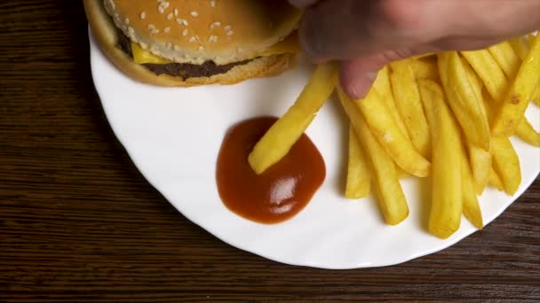 Verse zelfgemaakte hamburger met zwarte sesamzaadjes in witte plaat met frietjes aardappelen, geserveerd met ketchup saus in glazen pot over grijze houten oppervlak. Franse frietjes in ketchup met mini dompelen — Stockvideo