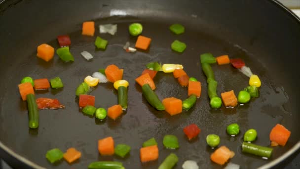 Нарезанные овощи в сковороде собираются в слове FOOD. Жареные овощи с мясом в сковороде. Перемешать жареные овощи в кастрюле — стоковое видео