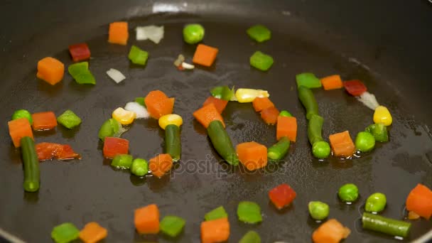 Нарезанные овощи в сковороде собираются в слове FOOD. Перемешать жареные овощи на сковороде. Овощи летят в воздухе, их переворачивают с сковороды. Вегетарианское питание — стоковое видео