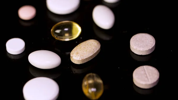 Pills spinning. Pile of several medicines. White tablets with pills on black background. Opened medicine capsule pill — Stock Photo, Image