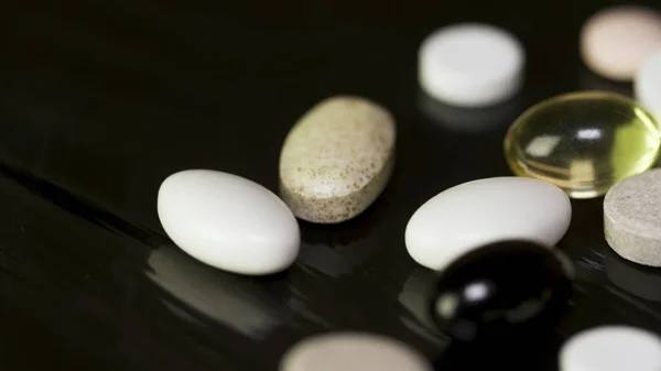 Pills spinning. Pile of several medicines. White tablets with pills on black background. Opened medicine capsule pill — Stock Photo, Image