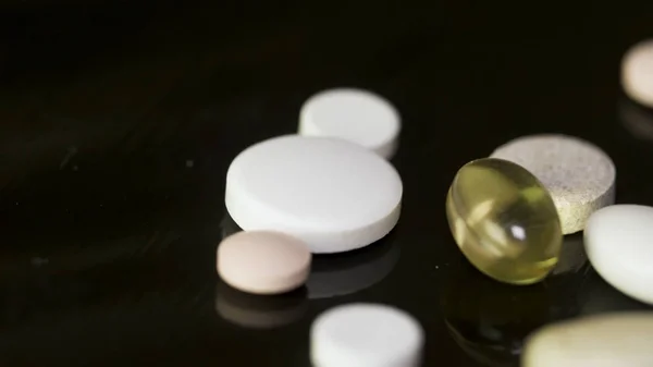 Pastilele se învârt. O grămadă de medicamente. Tablete albe cu pastile pe fundal negru. Tabletă de medicament deschisă — Fotografie, imagine de stoc
