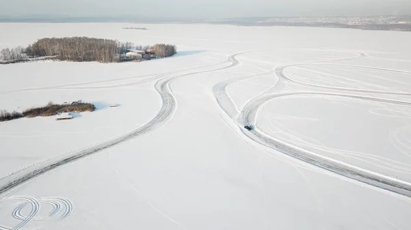 Een auto rijden door het bos van de winter op de landweg. Bovenaanzicht van een drone. Luchtfoto van sneeuw overdekte weg in de winter, passerende auto. Bovenaanzicht van de auto op besneeuwde weg reizen — Stockfoto
