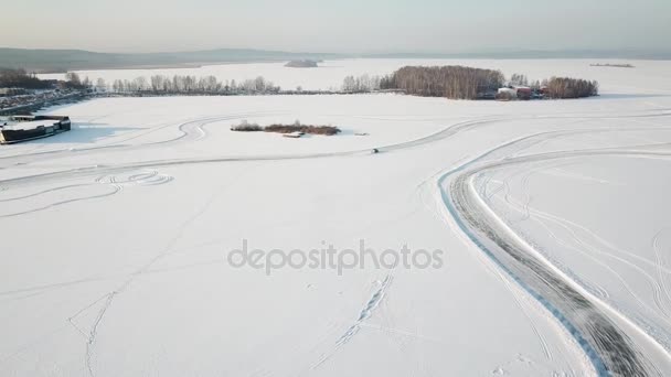 One car driving through the winter forest on country road. Top view from drone. Aerial view of snow covered road in winter, car passing by. Top view of the car traveling on snowy road — Stock Video