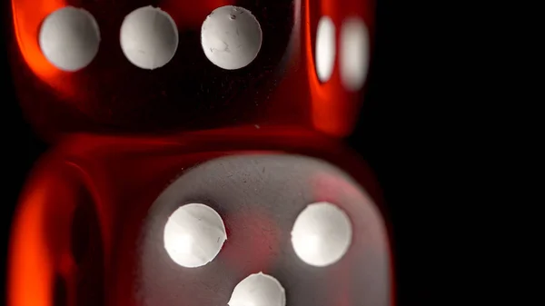 Two red casino dices on the black background. Shot glasses with dice and ribbon. risk concept - playing dice at black wooden background. Playing a game with dice. Red casino dice rolls.