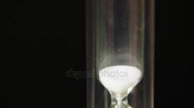 Zaman için siyah arka plan kavramı üzerinde bir kum saati üzerinden akan kum. Kum saati makro