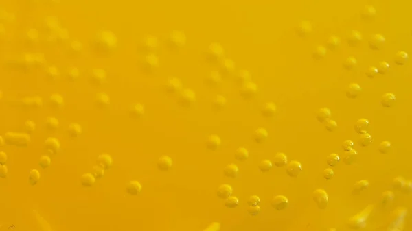 Orange soda with bubbles background. Fresh orange fruit in a glass of soda water. Orange summer drink with bubbles. Bubbles floating in the liquid orange drink.