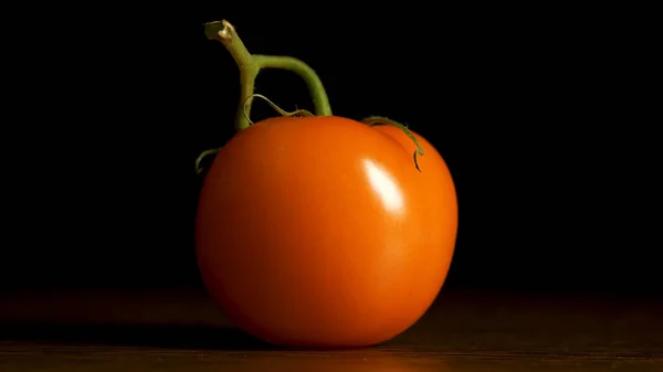 Rote Tomate auf schwarzem Hintergrund. Art mit einer Seite. Tomate Single mit Tropfen isoliert auf schwarz. frische Tomate auf schwarzem Hintergrund — Stockfoto