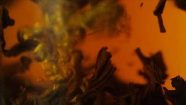 Un bollitore di vetro di tè nero, concetto di bevanda sana. Tè nero in primo piano acqua. Particelle di tè nero galleggiante in una teiera di vetro, prodotta, tè cinese, macro — Video Stock