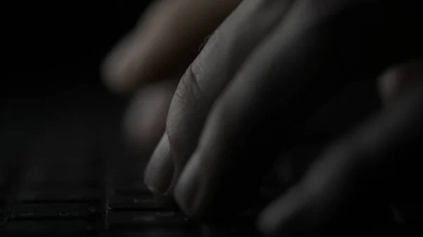 Pulsando el teclado del ordenador. Mano masculina está escribiendo texto en una macro portátil. Dedos presionando la tecla del teclado sobre fondo negro — Foto de Stock