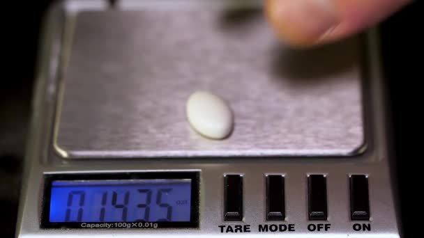 Le pharmacien, un travailleur de laboratoire en gants de caoutchouc stériles, pèse les comprimés fabriqués sur les balances témoins. Instruments de mesure et d'analyse du poids Balance analytique électronique .