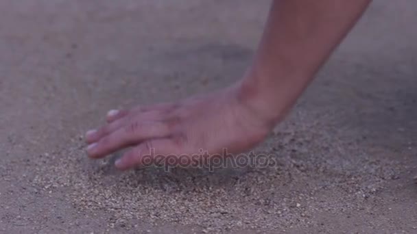 Close up of mans hand touching sand at the shore of the sea - concept of native place. man holds his hand over the sand on the beach - concept of vacations and tourism. Sand on the hand at green sand — Stock Video