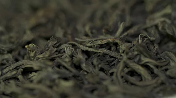Pozadí textury zeleného čaje Sencha - čerstvé, lahodné, jemné čaje. Černý čaj daleko do pozadí. Hromadu suchého černého čaje, textury. Makro snímek. — Stock fotografie