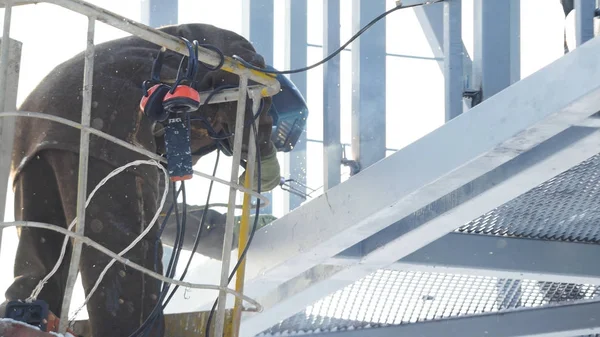 Lasser werken met elektrode bij booglassen in bouw site winter buiten. Lasser beschermend masker werken buiten in de winter close-up — Stockfoto