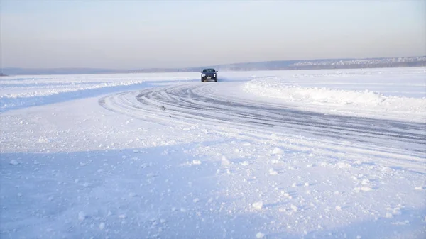 Coche con neumáticos de invierno instalado en llantas de aleación ligera en carretera nevada al aire libre. Un coche que conduce por una carretera nevada durante el invierno. Conduce en un camino nevado —  Fotos de Stock