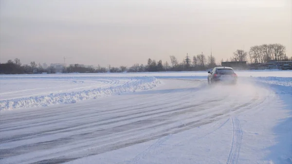 Coche con neumáticos de invierno instalado en llantas de aleación ligera en carretera nevada al aire libre. Un coche que conduce por una carretera nevada durante el invierno. Conduce en un camino nevado —  Fotos de Stock