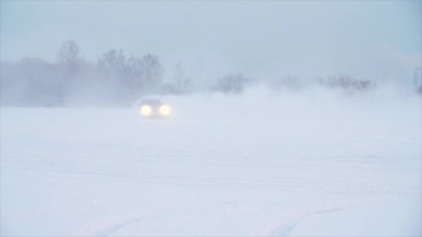 Route enneigée dans la forêt avec voiture et faire un 180 tourner au ralenti. La voiture dérive dans la neige. Balades en voiture sur une route enneigée en hiver — Video