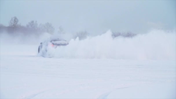 Snowy road in forest with car by and making a 180 turn slow motion. Машина делает дрейф в снегу. Прогулки на машине по снежной дороге зимой — стоковое видео