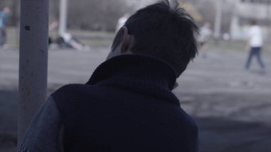 Yalnız çocuk bankta oturur ve arkadaşları futbol oynamak gibi izliyor. Yalnız çocuk bankta oturuyor ve diğerleri futbol oynamak dikkat et. Yedek oyuncu. Yalnızlık kavramını