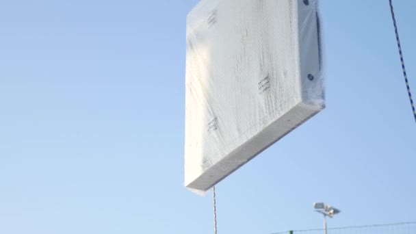 Os homens montam Billboard na torneira. Construtor em uma plataforma de elevação em um canteiro de obras. Homem sobe para a parte superior da Billboard para publicidade — Vídeo de Stock