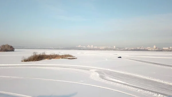 在雪地跑道上驾驶汽车的鸟瞰图。一辆汽车驶过乡间小路的冬季森林。顶级视图从无人机 — 图库照片