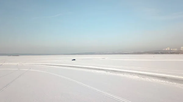 Luchtfoto op het besturen van de auto op besneeuwde circuit. Een auto rijden door het bos van de winter op de landweg. Bovenaanzicht van drone — Stockfoto