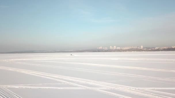 Vista aérea en coche de conducción en pista nevada. Un coche que conduce a través del bosque de invierno en la carretera del campo. Vista superior desde el dron — Vídeos de Stock