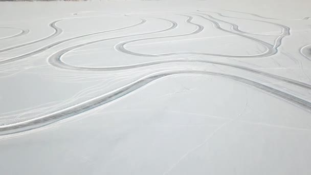 Зимний пейзаж со следами шин на снегу выходит на горизонт, солнце и облака в небе. Снежная пустыня и следы машины в снегу. Следы на снегу — стоковое видео