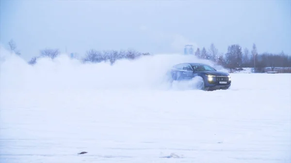Samochód idzie w śniegu. Samochód jeździ na zaśnieżonej drodze poza miastem. Duży crossover jeździ na śniegu — Zdjęcie stockowe