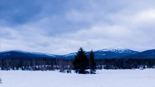 Carretera, montaña nevada y cielo azul con nubes blancas bajo la luz del sol invernal. Terreno cubierto de nieve montañosa. Cronograma — Vídeo de stock