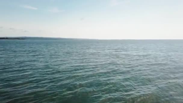 岸に近い海の上から日ビューを反映して多くの小さな波の形成の下の砂に近い青緑色の水 — ストック動画